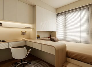 A timber study desk beside a window and bed, with cream overhead cabinetry