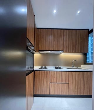 Wood-tone kitchen cabinetry with a light countertop and under-cabinet lighting